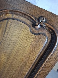 Ręcznie rzeźbione detale na drewnianej powierzchni kredensu.