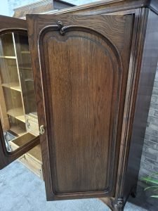 Klasyczne drewniane drzwi kredensu z dekoracyjną ramą i uchwytami.