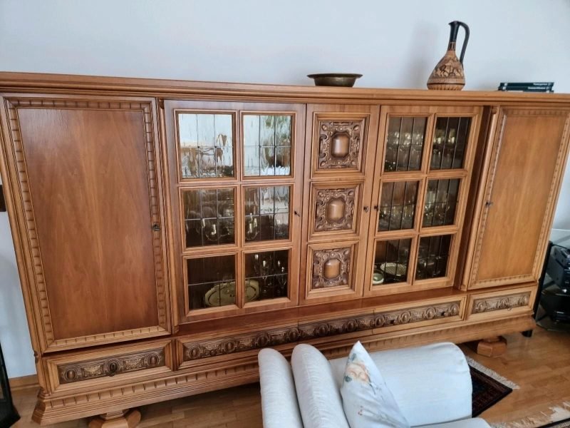 Klasyczna drewniana witryna z rzeźbionymi detalami i przeszklonymi drzwiami – mebel do stylizacji.